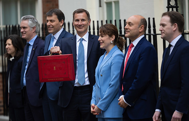 The Chancellor of the Exchequer Jeremy Hunt, accompanied by his ministerial team and watched by his wife and children, leaves 11 Downing Street on his way to deliver the budget.