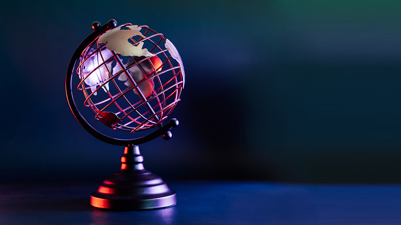 Metallic model of a globe with map in blue and red neon light. Bipolarity of the world. Geography concept. Selective focus