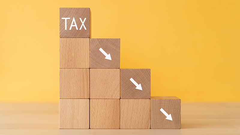 Decreasing tax; Wooden blocks with "TAX" text of concept.