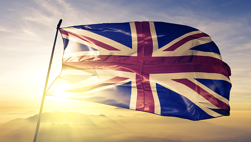 United Kingdom British english flag on flagpole textile cloth fabric waving on the top sunrise mist fog