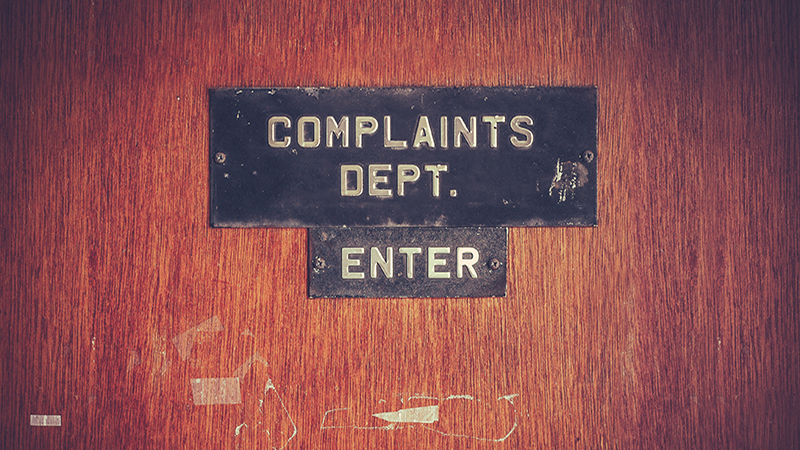 Retro Filtered Image Of A Grungy Complaints Department Sign On A Door