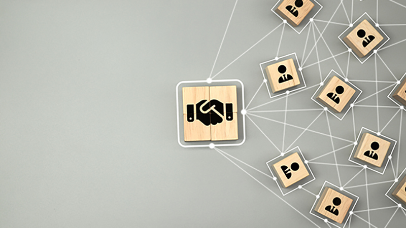 Hand shake icon on wooden cube block which connection with human icon for business deal and agreement concept.