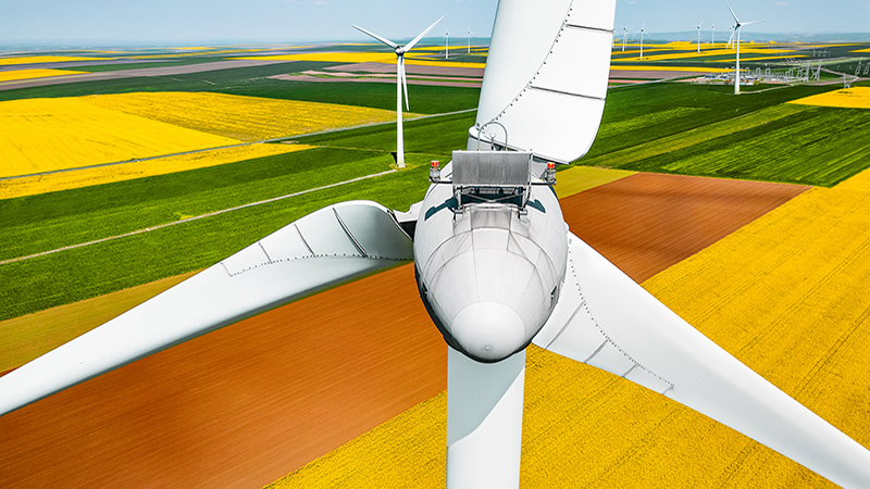Drone view of wind turbines farm on yellow field