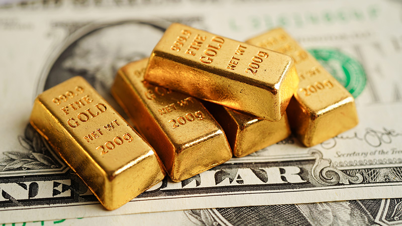 Gold bars on US dollar banknote money, finance trading investment business currency concept.