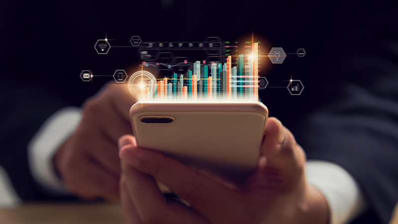 Stock exchange market concept, hand trader holding smartphone with graphs analysis candle line on bokeh colors light in night.