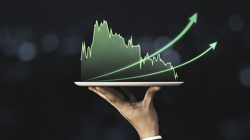 Businessman holding mobile & tablet which showing green technical stock investment graph with increase arrow. Value investor and analysis data concept.