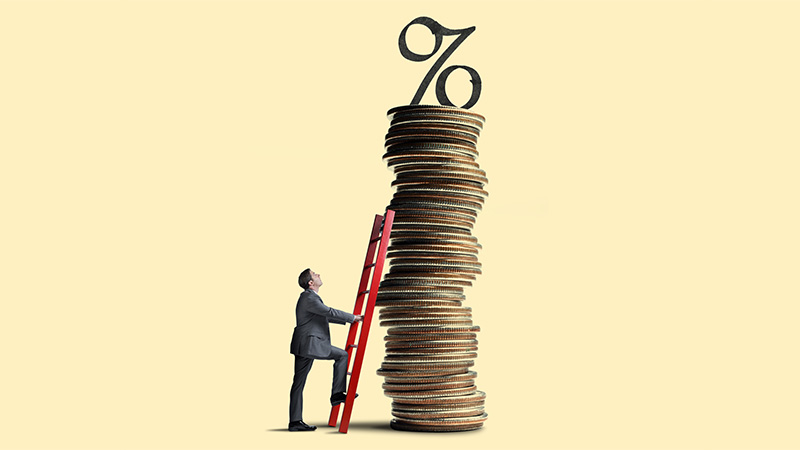 A man looks up as he leans a red ladder against a tall stack of coins that is topped with an interest rate symbol.