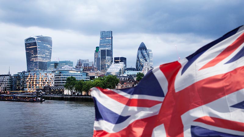 union jack flag over London financial district with iconic skyscrapers, UK prepares for elections after Brexit