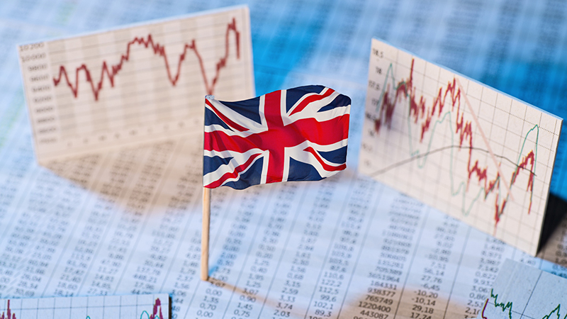 British flag with exchange rate tables and graphs on economic development