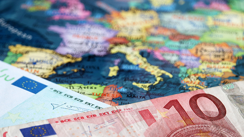 Euro banknotes on the map of Europe, selective focus. Concept for european economy, eurozone countries