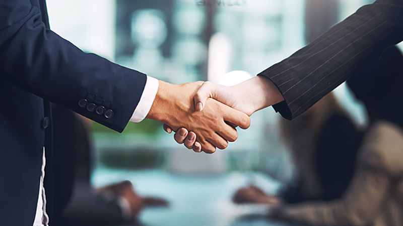 Cropped shot of a businessman and businesswoman shaking hands in a modern office