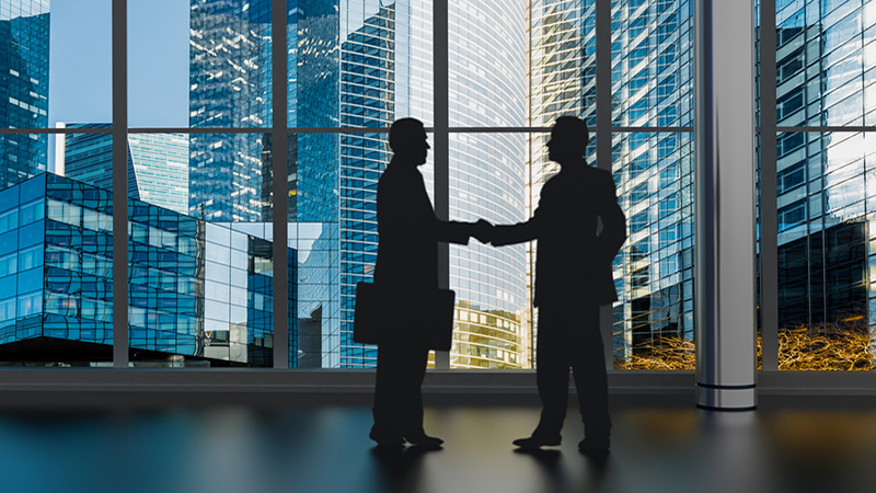 businessman shaking hands inside a business tower