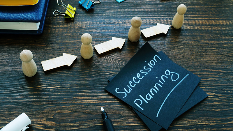 Succession planning sign and figurines with arrows.