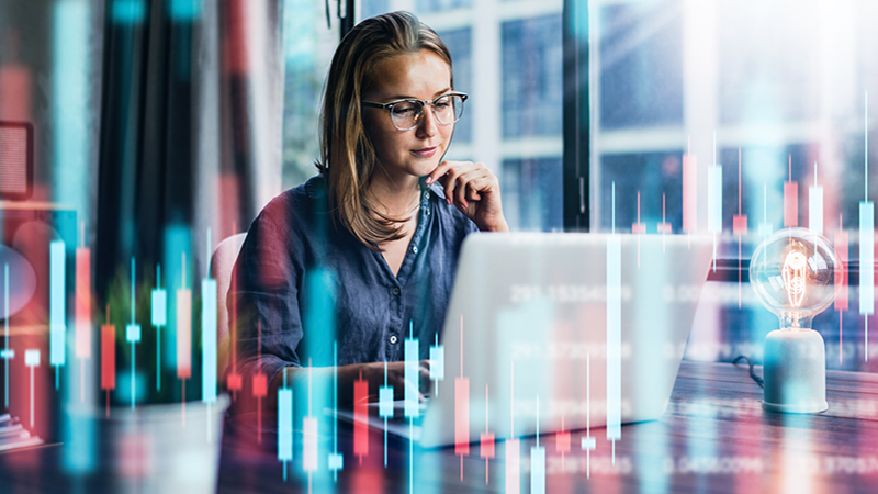 Young woman working at modern office.Technical price graph and indicator, red and green candlestick chart and stock trading computer screen background. Double exposure. Trader analyzing data